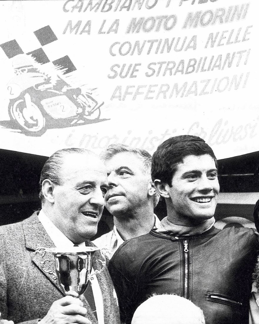 Piloto de Moto Morini celebra un triunfo con su trofeo, foto de archivo