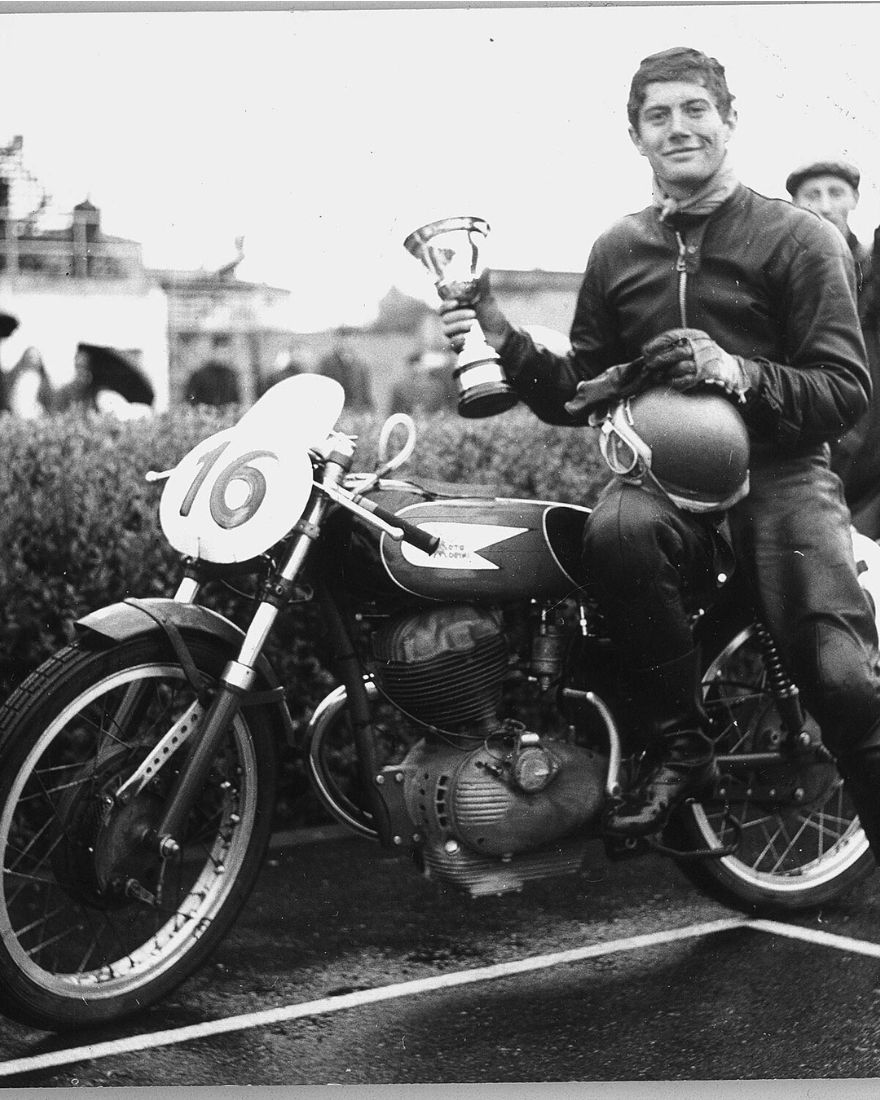 Piloto con trofeo sobre una Moto Morini de carrera, número 16